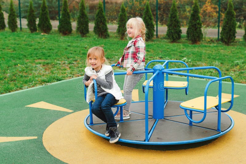 Amici felici divertendosi sul carosello all'aperto Bambine sveglie che godono al campo da giuoco Infanzia felice e sana moderno fotografia stock libera da diritti Amici felici divertendosi sul carosello all'aperto Bambine sveglie che godono al campo da giuoco Infanzia felice e sana moderno fotografia stock libera da diritti