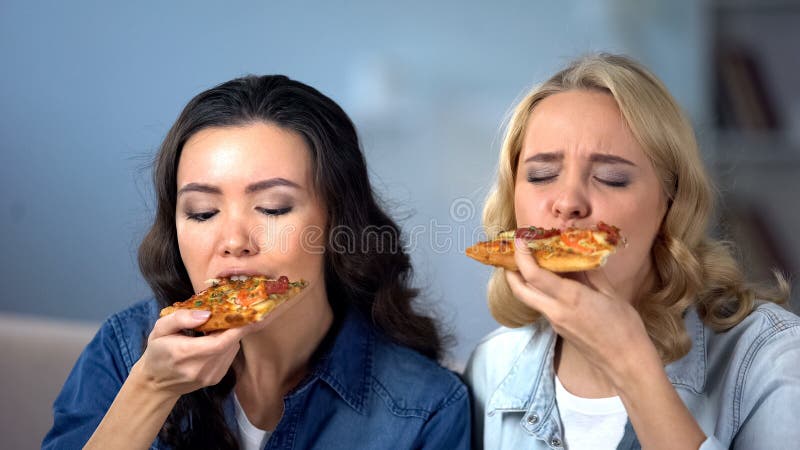 Amici femminili affamati che godono della pizza deliziosa, cucina italiana, consegna dell'alimento fotografia stock Amici femminili affamati che godono della pizza deliziosa, cucina italiana, consegna dell'alimento fotografia stock
