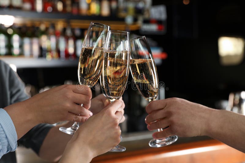 Amici tintinnanti con i vetri di champagne nella barra fotografia stock Amici tintinnanti con i vetri di champagne nella barra fotografia stock