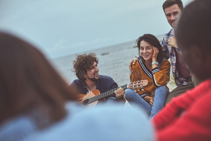 Amico che gioca la chitarra alla spiaggia fotografia stock libera da diritti Amico che gioca la chitarra alla spiaggia fotografia stock libera da diritti