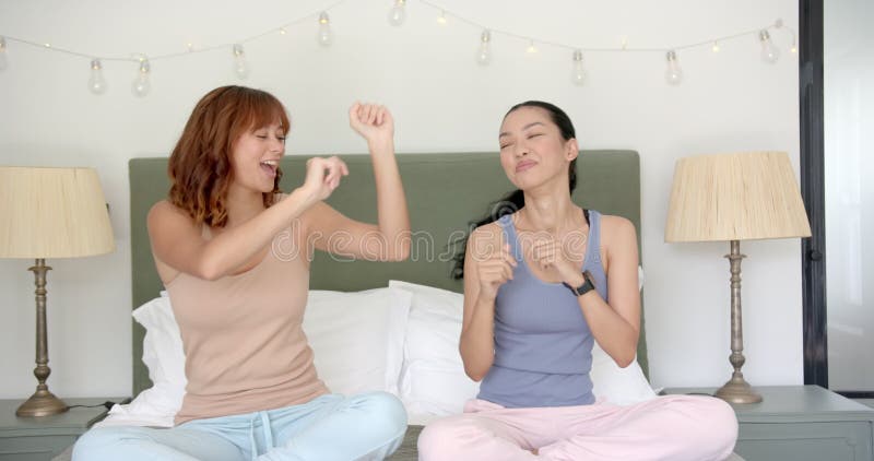 Amies filles Biracy danser et s'amuser sur un lit clips vidéos
