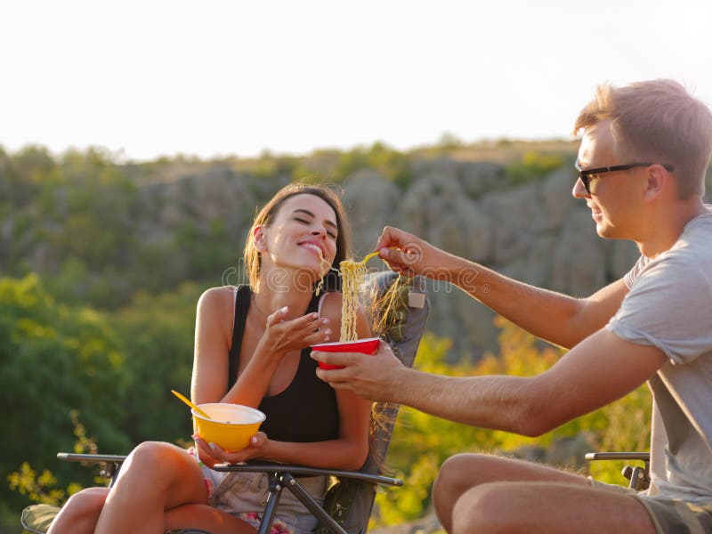 Amiga e noivo que comem macarronetes em um fundo natural Pares felizes do turista que têm o divertimento Conceito barato do turis fotografia de stock royalty free Amiga e noivo que comem macarronetes em um fundo natural Pares felizes do turista que têm o divertimento Conceito barato do turis fotografia de stock royalty free