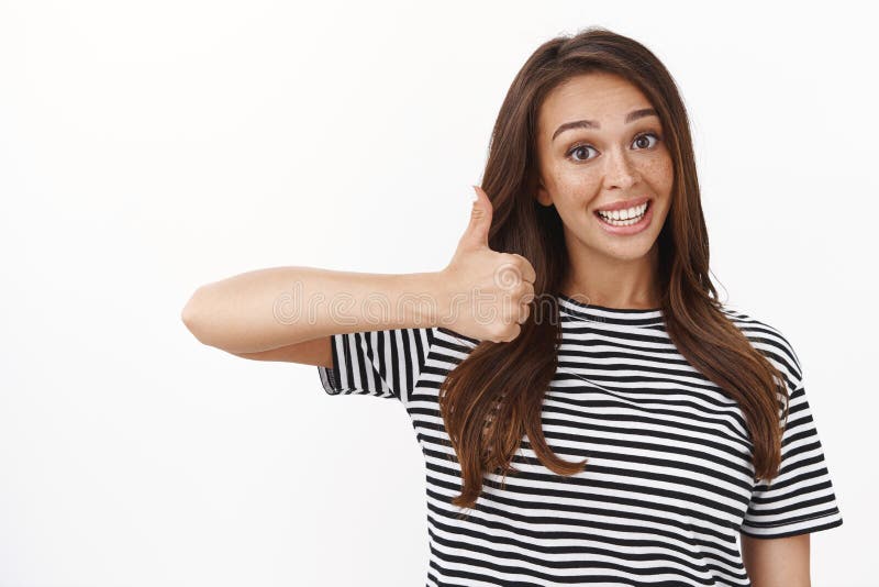 Amigable y simpática guapa mujer morena animando a un amigo, animándolo a seguir intentando, mostrar el pulgar arriba en aprobaci fotografía de archivo libre de regalías