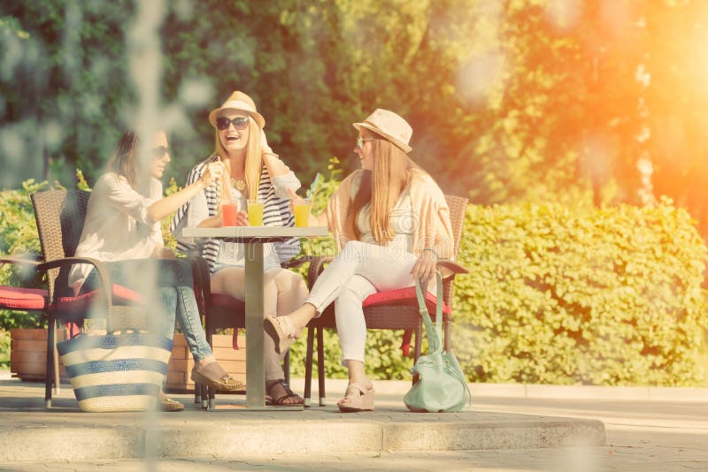 Amigas que apreciam cocktail em um café exterior, conceito da amizade foto de stock