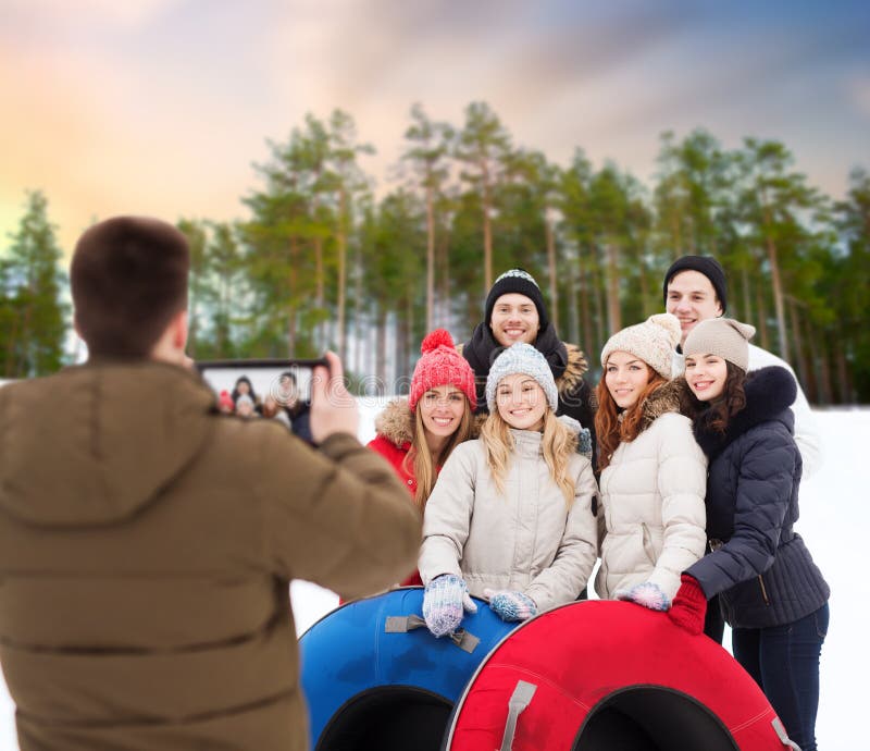 Amigos con los tubos de la nieve que toman la foto por la PC de la tableta fotos de archivo libres de regalías Amigos con los tubos de la nieve que toman la foto por la PC de la tableta fotos de archivo libres de regalías