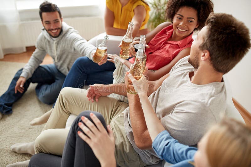 Amigos felices que beben el partido de la cerveza en casa imágenes de archivo libres de regalías Amigos felices que beben el partido de la cerveza en casa imágenes de archivo libres de regalías