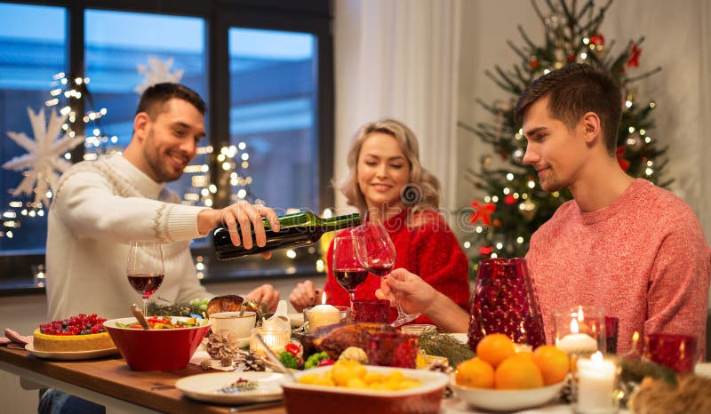 Amigos felizes que bebem o vinho tinto na festa de Natal imagem de stock royalty free
