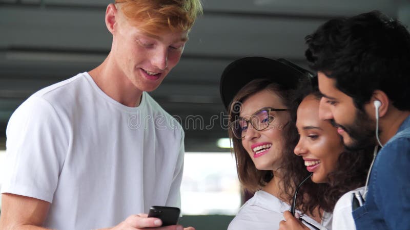 Amigos felizes que usam o telefone celular no parque de estacionamento