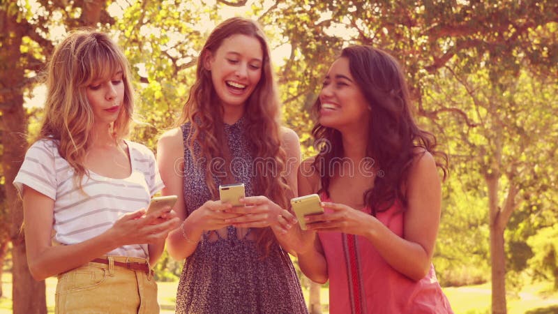 Amigos femeninos felices que usan sus smartphones y risa