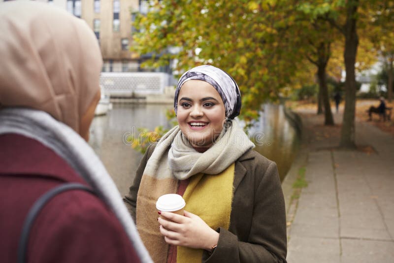 Amigos femeninos musulmanes británicos que hablan por el río en ciudad fotografía de archivo Amigos femeninos musulmanes británicos que hablan por el río en ciudad fotografía de archivo