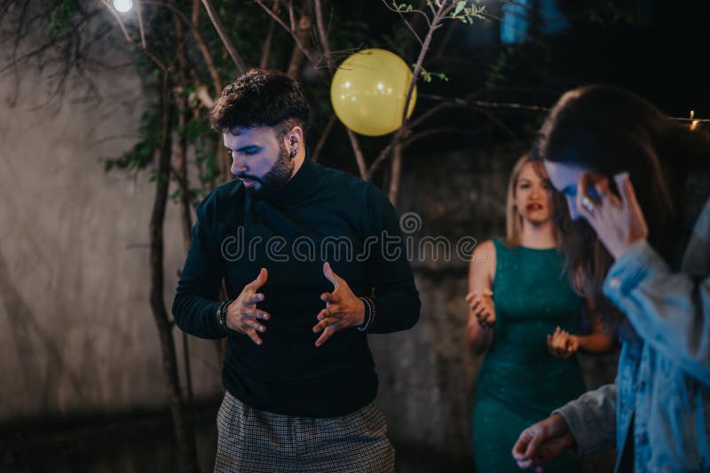 Amigos interactuando en una fiesta al aire libre con decoración festiva e iluminación imagen de archivo