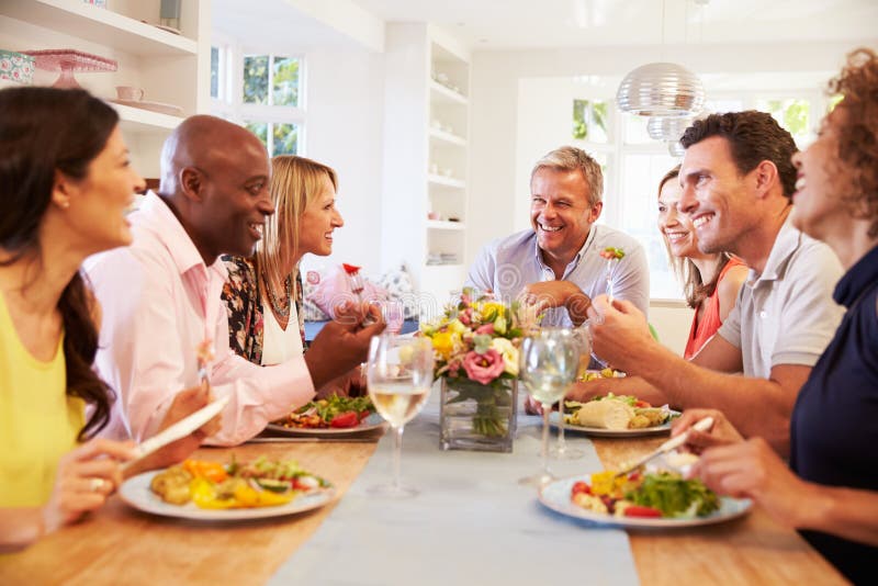 Mature Friends Sitting Around Table At Dinner Party. Mature Friends Sitting Around Table At Dinner Party