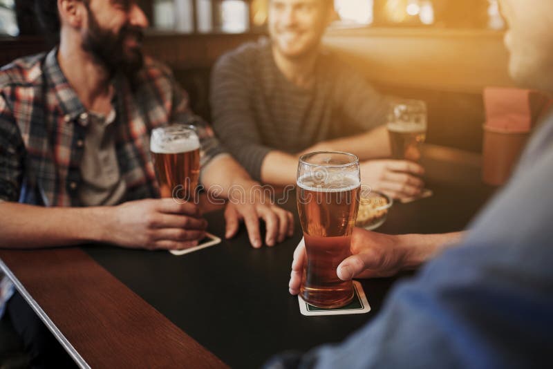 Amigos masculinos felices que beben la cerveza en la barra o el pub fotografía de archivo libre de regalías Amigos masculinos felices que beben la cerveza en la barra o el pub fotografía de archivo libre de regalías