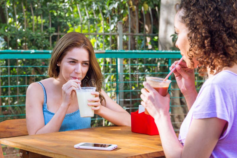 Amigos multi-étnicos com suco bebendo com palhas fora na cidade de Sao Paulo durante a luz brilhante do dia de verão Conceito d imagens de stock Amigos multi-étnicos com suco bebendo com palhas fora na cidade de Sao Paulo durante a luz brilhante do dia de verão Conceito d imagens de stock
