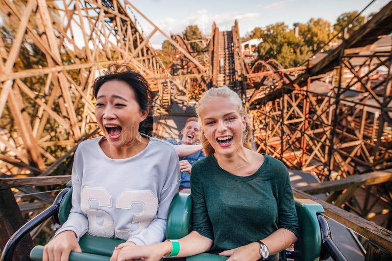 Shot of young friends riding roller coaster ride at amusement park. Young people having fun at amusement park. Shot of young friends riding roller coaster ride at amusement park. Young people having fun at amusement park.