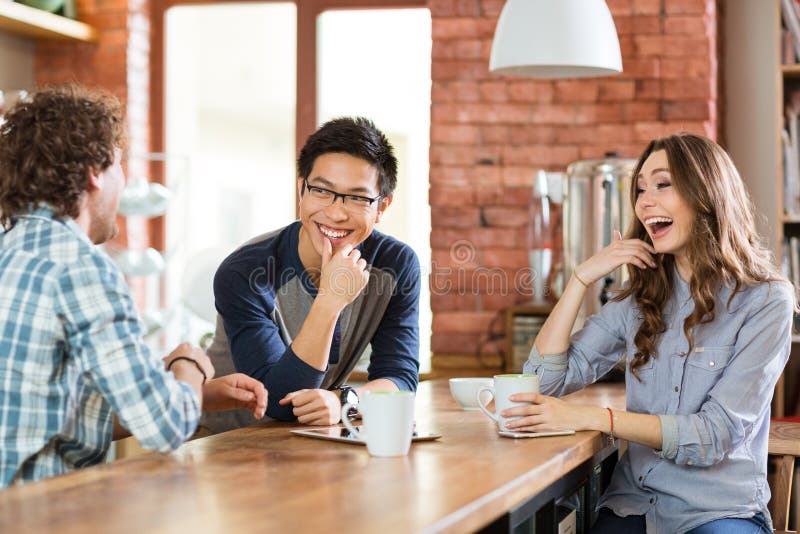 Amigos positivos felizes que riem no café imagens de stock Amigos positivos felizes que riem no café imagens de stock