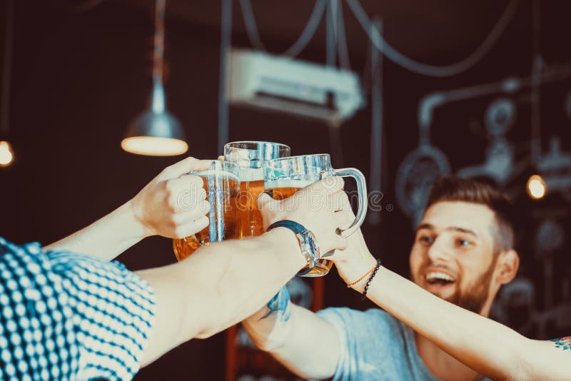 Amigos que brindam com vidros da cerveja clara no bar imagens de stock Amigos que brindam com vidros da cerveja clara no bar imagens de stock