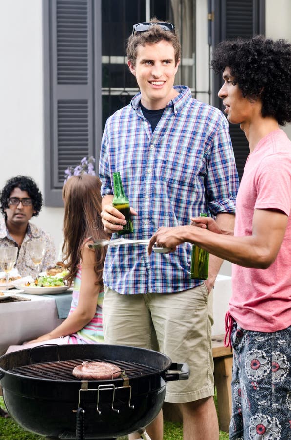 Amigos que enlazan sobre el Bbq con las cervezas a disposición imagen de archivo Amigos que enlazan sobre el Bbq con las cervezas a disposición imagen de archivo