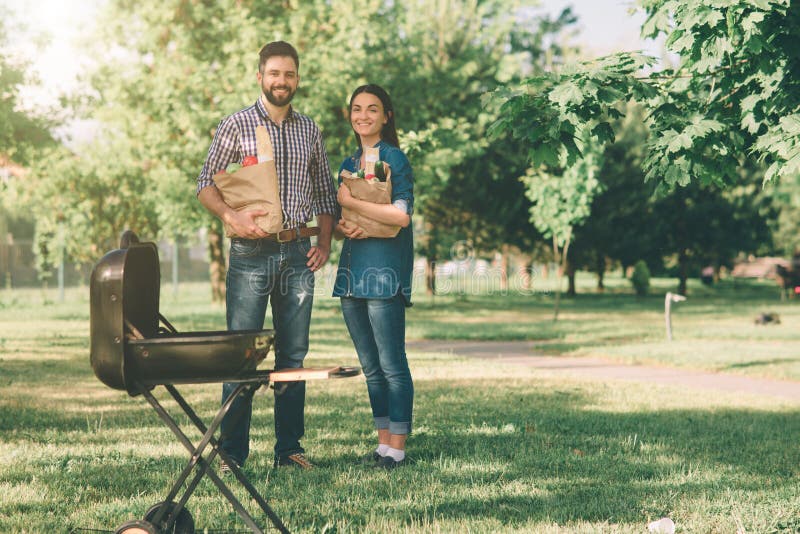 Amigos que hacen la barbacoa y que almuerzan en la naturaleza Junte divertirse mientras que come y bebe en una comida campestre - fotografía de archivo Amigos que hacen la barbacoa y que almuerzan en la naturaleza Junte divertirse mientras que come y bebe en una comida campestre - fotografía de archivo