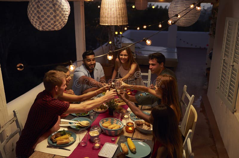 Amigos que hacen una tostada en un partido de cena en un patio, Ibiza imagenes de archivo Amigos que hacen una tostada en un partido de cena en un patio, Ibiza imagenes de archivo