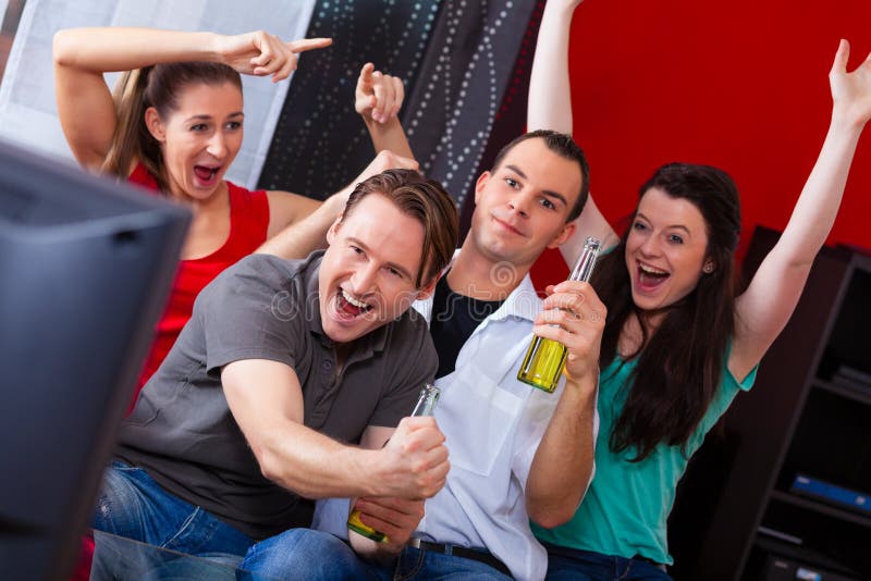 Amigos que miran el juego emocionante en la TV imágenes de archivo libres de regalías Amigos que miran el juego emocionante en la TV imágenes de archivo libres de regalías