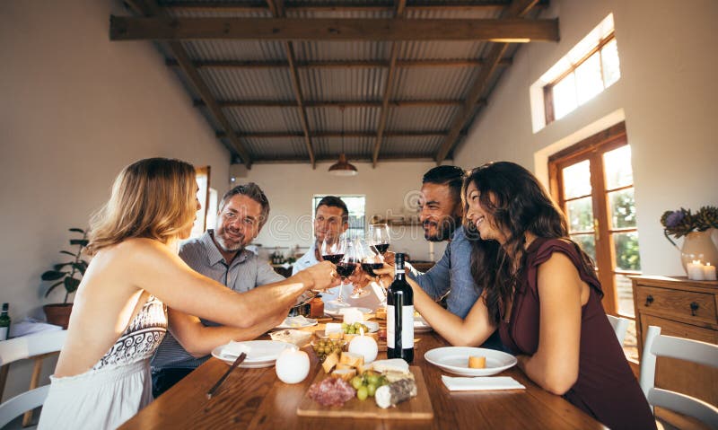 Amigos que se divierten con el partido del vino y de la comida en casa imagenes de archivo Amigos que se divierten con el partido del vino y de la comida en casa imagenes de archivo