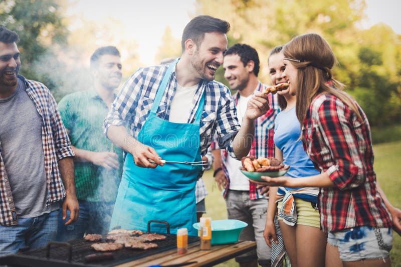 Amigos que tienen un partido de la barbacoa en naturaleza imagen de archivo libre de regalías Amigos que tienen un partido de la barbacoa en naturaleza imagen de archivo libre de regalías