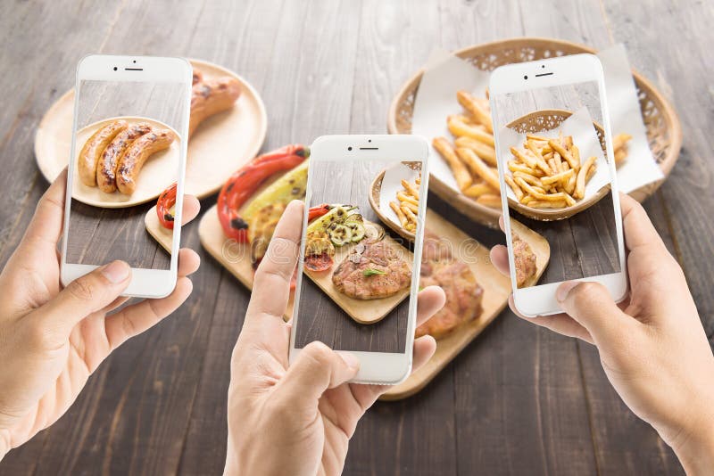 Amigos que usan smartphones para tomar las fotos del cho de la salchicha y del cerdo foto de archivo libre de regalías Amigos que usan smartphones para tomar las fotos del cho de la salchicha y del cerdo foto de archivo libre de regalías