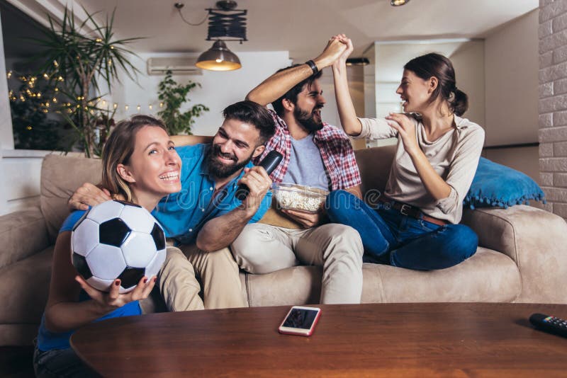 Conceitual assistir jogo de futebol no sofá na televisão com garrafas de  cerveja e tigela de pipoca em amigos apreciando jogo de futebol TV fotos,  imagens de © TheVisualsYouNeed #193389504