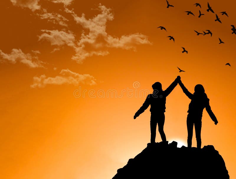 At sunset,friends on Top of a Mountain Shaking Raised Hands. At sunset,friends on Top of a Mountain Shaking Raised Hands