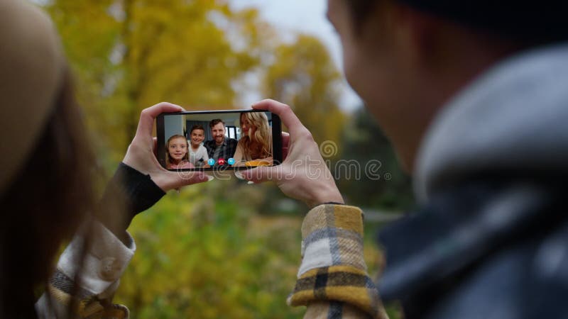 Amis agitant l'application virtuelle closeup. couple joyeux parler en famille en ligne à l'extérieur banque de vidéos