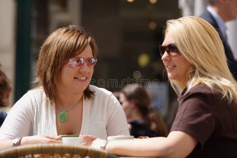 Two young ladies having coffee in the sun. Two young ladies having coffee in the sun