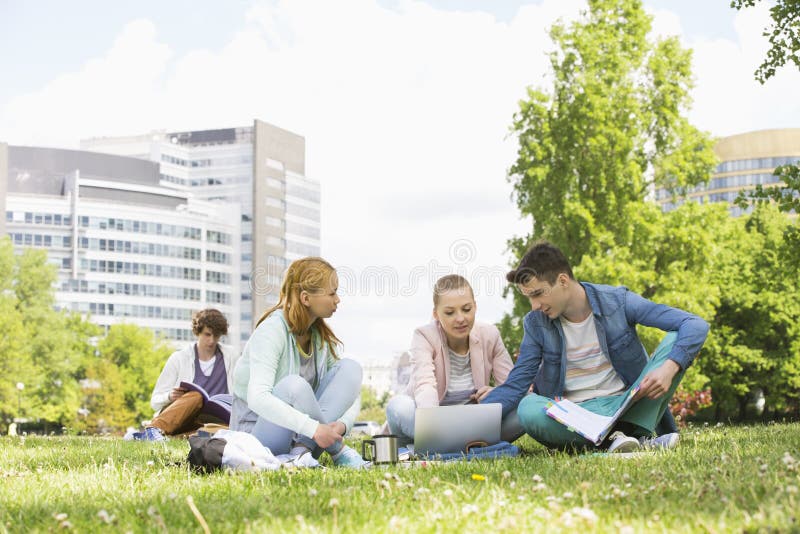 College friends studying while using laptop at campus. College friends studying while using laptop at campus