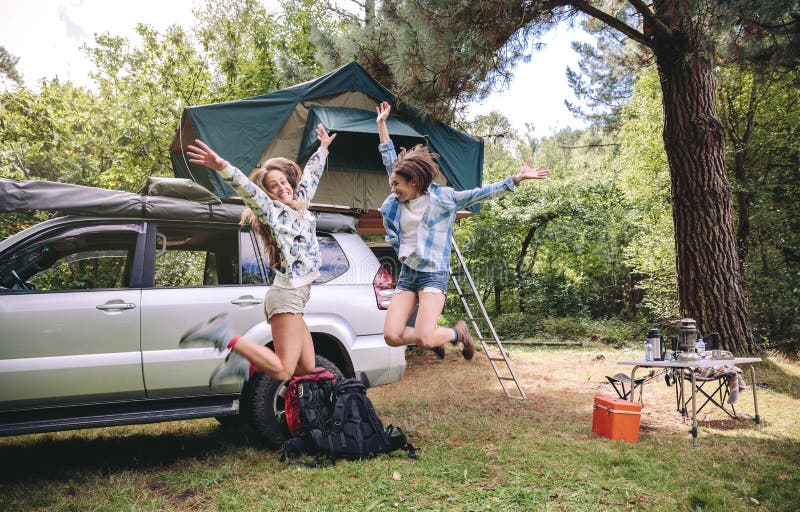 Amis de femmes sautant dans le terrain de camping dans la forêt photos stock Amis de femmes sautant dans le terrain de camping dans la forêt photos stock
