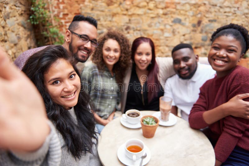 Amis divers prenant des selfies dans une cour à la mode de café photos stock Amis divers prenant des selfies dans une cour à la mode de café photos stock