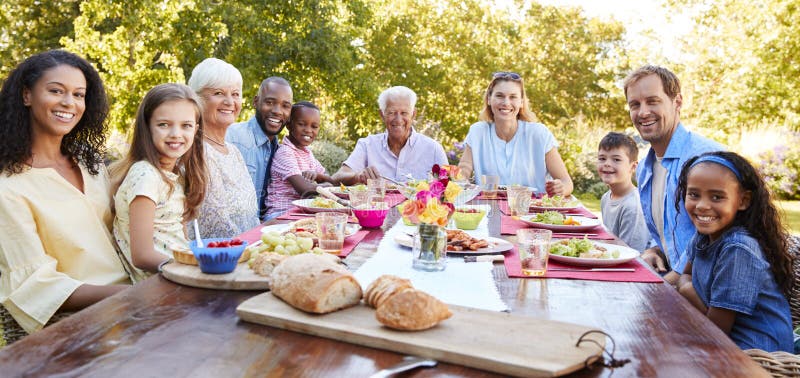Amis et famille prenant le déjeuner dans le jardin, regardant à l'appareil-photo photo libre de droits Amis et famille prenant le déjeuner dans le jardin, regardant à l'appareil-photo photo libre de droits