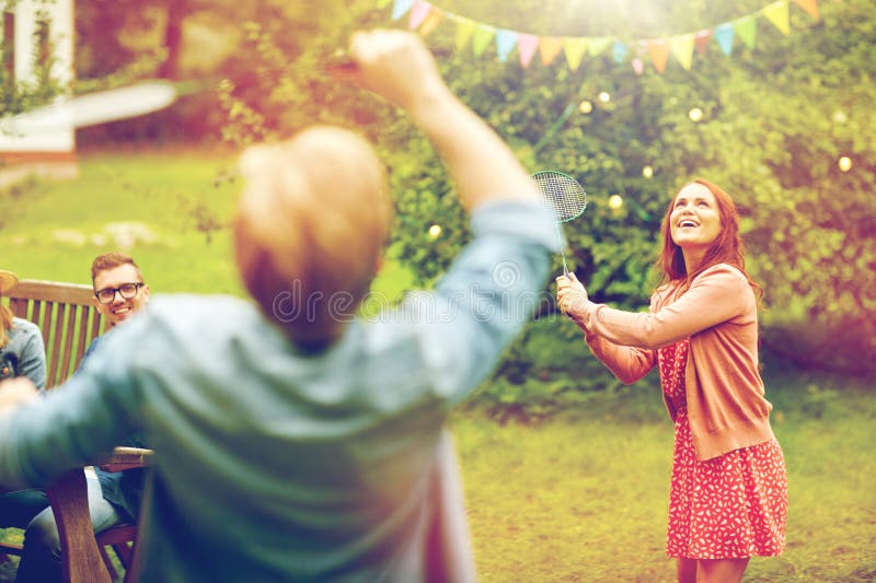 Amis heureux jouant le badminton au jardin d'été image stock Amis heureux jouant le badminton au jardin d'été image stock