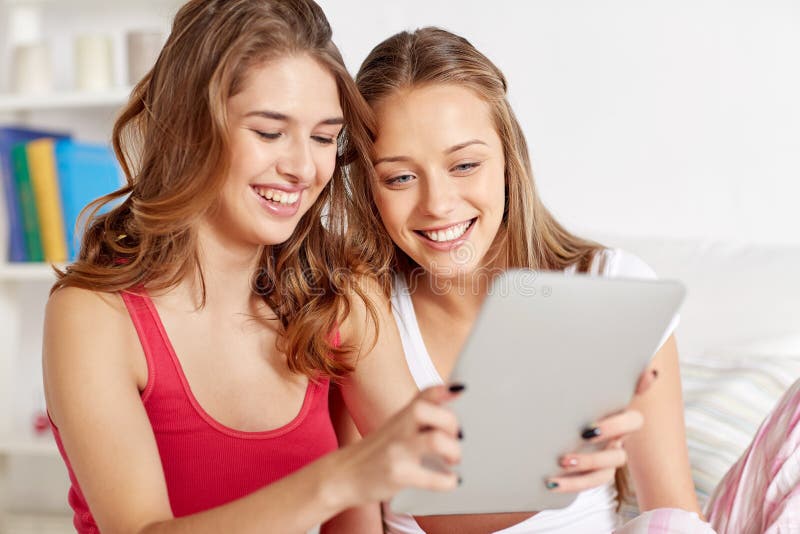 Amis heureux ou filles de l'adolescence avec le PC de comprimé à la maison photographie stock libre de droits Amis heureux ou filles de l'adolescence avec le PC de comprimé à la maison photographie stock libre de droits