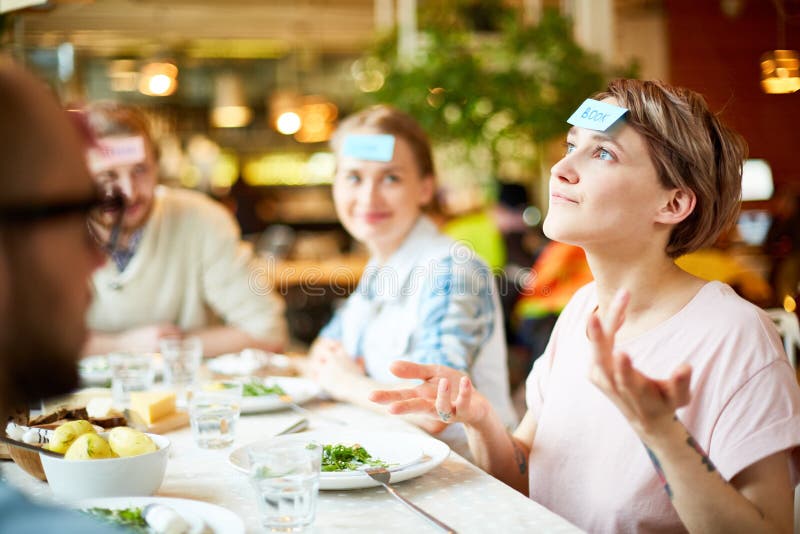 Amis jouant le jeu dans le restaurant images libres de droits Amis jouant le jeu dans le restaurant images libres de droits