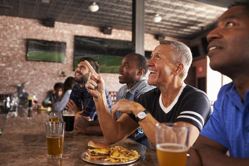 Amis masculins au compteur dans le jeu de observation de barre de sports photos libres de droits Amis masculins au compteur dans le jeu de observation de barre de sports photos libres de droits