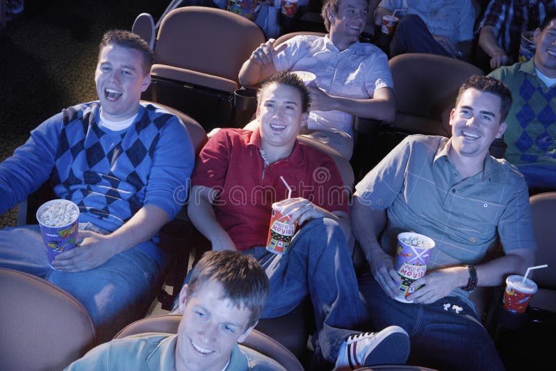 Group of multiethnic male friends watching movie in theater. Group of multiethnic male friends watching movie in theater