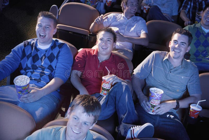 Amis masculins observant le film dans le théâtre photo stock Amis masculins observant le film dans le théâtre photo stock