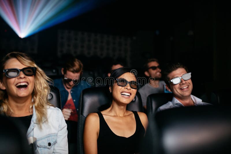 Group of young friends watching 3d movie in theater and laughing. Young men and women wearing 3d glasses in cinema hall. Group of young friends watching 3d movie in theater and laughing. Young men and women wearing 3d glasses in cinema hall.