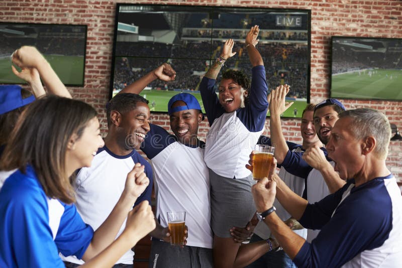 Amis observant le jeu dans la barre de sports sur la célébration d'écrans image libre de droits Amis observant le jeu dans la barre de sports sur la célébration d'écrans image libre de droits