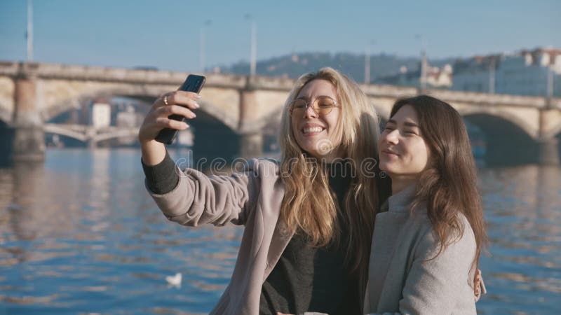 Amis positifs marchant dehors et partageant l'humeur à l'aide du téléphone portable. portrait de beaux amis souriant sur la banque de vidéos