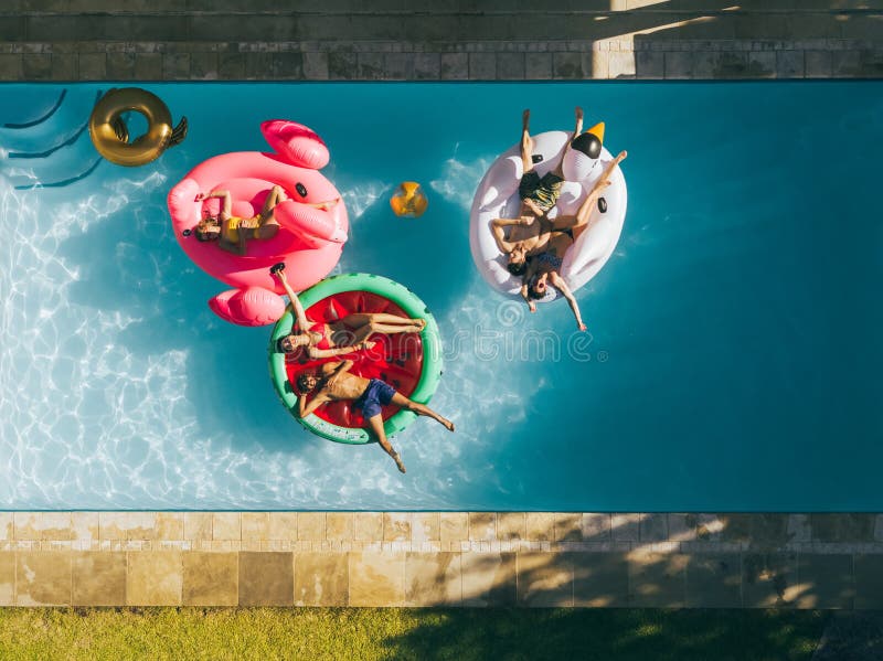 Amis refroidissant sur des matelas d'air dans la piscine photo stock Amis refroidissant sur des matelas d'air dans la piscine photo stock