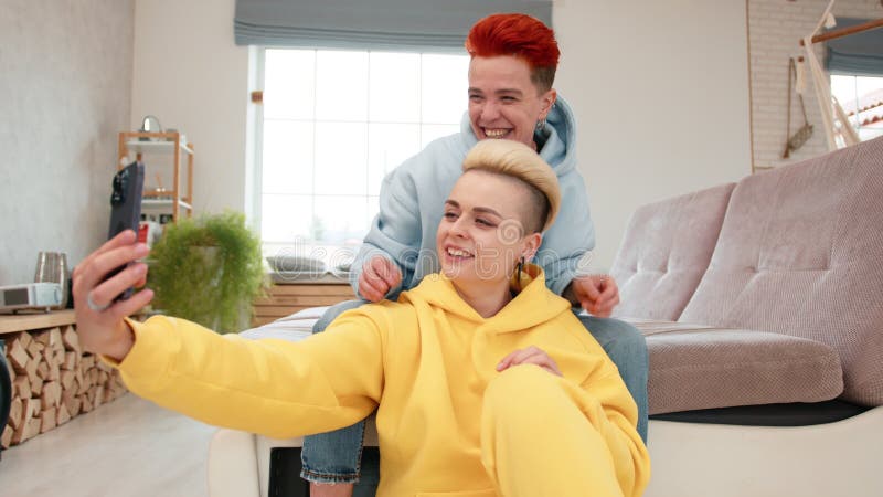 Amis s'amuser à prendre des selfies à la maison dans des tenues décontractées dans un salon confortable banque de vidéos