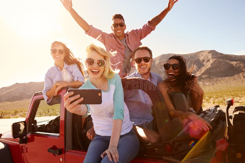 Amis sur le voyage par la route dans la voiture convertible prenant Selfie photos libres de droits Amis sur le voyage par la route dans la voiture convertible prenant Selfie photos libres de droits