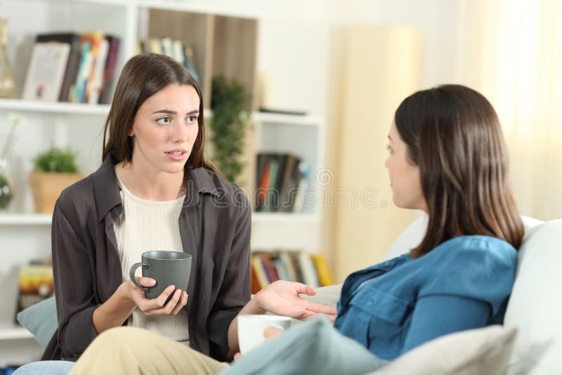 Serious friends talking sitting on a couch in the living room at home. Serious friends talking sitting on a couch in the living room at home