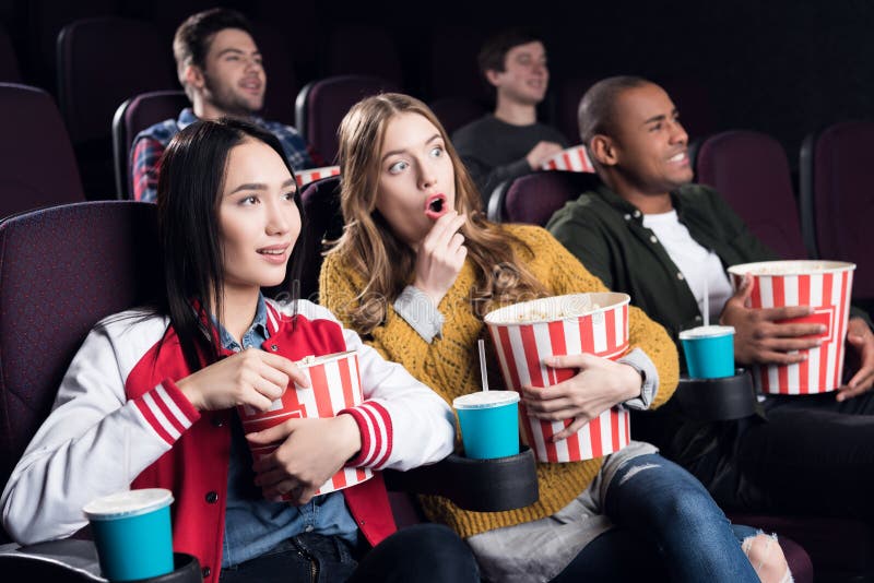 emotional friends with popcorn and soda watching movie in cinema. emotional friends with popcorn and soda watching movie in cinema